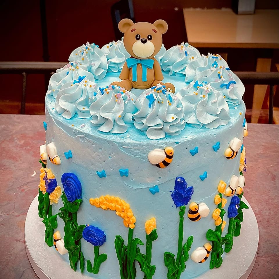 Elmwood Pastry Shop's blue cake with a teddy bear, bees, and flowers made of frosting.