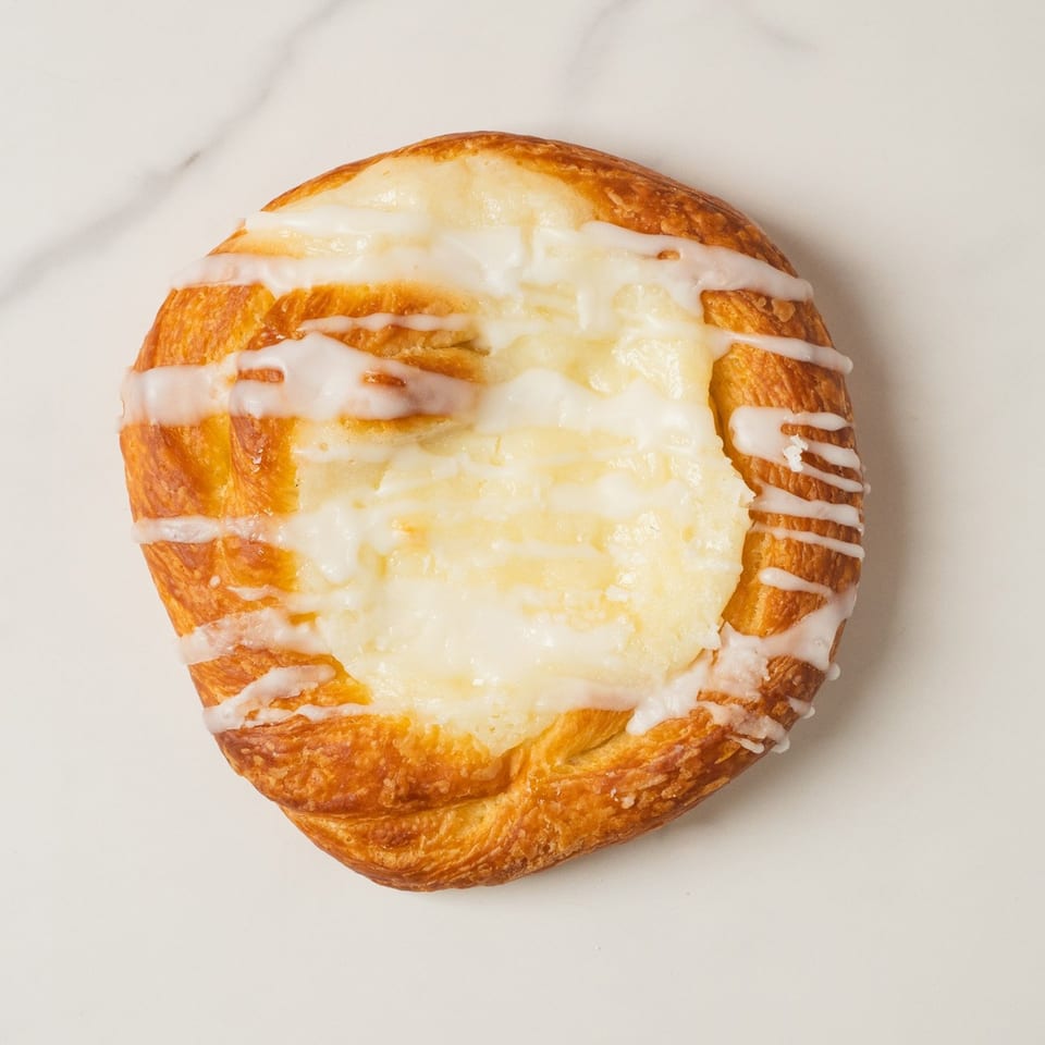 Elmwood Pastry Shop's cheese danish, a golden pastry with a creamy white center and icing drizzle.